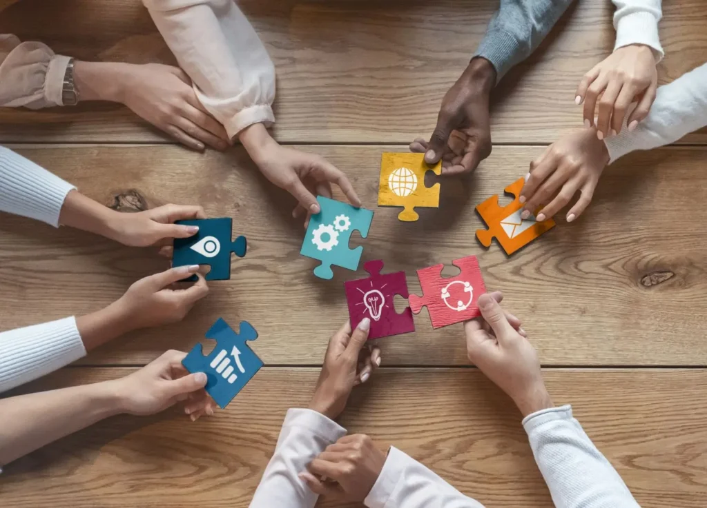 a group of people holding pieces of puzzle on a wooden table