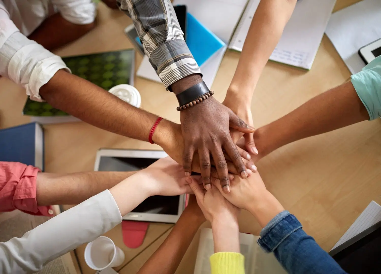 a group of people with their hands in the middle of a table
